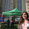 Rebecca Peterniak est debout devant un kiosque d’information de la Ville de Winnipeg. Elle sourit, le visage au soleil. 