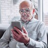 Un logiciel de reconnaissance faciale scanne le visage d'un homme âgé tenant un téléphone intelligent.