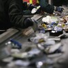 Des employés trient le contenu de bacs de recyclage à une usine.