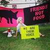 Regan Russell assise dans l'herbe autour d'affiches dénonçant l'abattage des animaux.