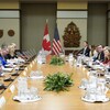 Le cortège ministériel canadien à droite fait face à ses homologues américains à gauche, tous assis à une longue table.