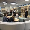 Des enfants assis sur des divans devant des tables et des bibliothèques au mur. 