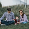 Ronna Sigua est assise dans un espace vert avec son enfant et son conjoint. 