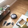 Un aspirateur robot évite des objets au sol dans un salon. 