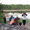 Une demi-douzaine de personnes observent un marais avec des jumelles.