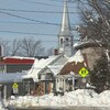 Paysage d'hiver où on voit des maisons et le pignon de l'église