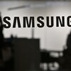 Le logo de Samsung est affiché avec des ombres de personnes en arrière-plan.