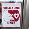 Une affiche annonce qu'un commerce propose de la naloxone, utilisée pour neutraliser les surdoses d'opioïdes.