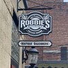 Un panneau publicitaire de l'entreprise Robbie's Sausage Company suspendu haut sur le mur.