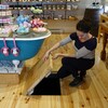Une femme ouvre une trappe au niveau du plancher dans un boutique de savon.