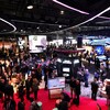 Beaucoup de gens circulent entre des kiosques d'entreprises de télécommunications, dans un grand espace avec plusieurs écrans. 