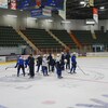 Une équipe de hockey s'entraînent sur la glace d'un aréna.