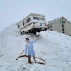 Un personnage en carton vide les toilettes de son véhicule récréatif pris dans un banc de neige à trois mètres dans les airs.