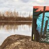 Un livre de Sébastien Gagnon repose sur un rocher se trouvant à proximité d'un cours d'eau. 