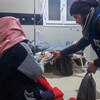 Un bénévole distribue des denrées à une victime du séisme en Syrie.