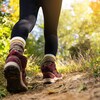 Plan rapproché des chaussures d'une femme sur un sentier dans la nature, en été, et qui marche dans la direction opposée de la caméra. 
