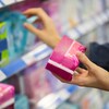 Une femme tient un paquet de serviettes hygiéniques dans un supermarché.
