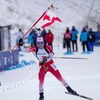 La biathlète sourit avant de croiser le fil d'arrivée.