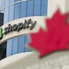Le logo de Shopify se détache sur la façade de l'immeuble, derrière une feuille d'érable.