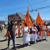 Des hommes portant turbans et drapeaux marchent au milieu de la rue.