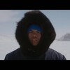 Un jeune homme portant un capuchon regarde devant lui dans un environnement arctique. 
