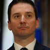 Simon Jolin-Barrette est debout devant des drapeaux du Québec.