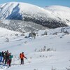 Plusieurs personnes sont en ski sur une montagne enneigée. 