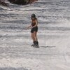 Une planchiste dévale une piste en short et en manches courtes. 