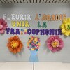 Le slogan écrit sur un mur d'école, avec des décorations de fleurs en papier.