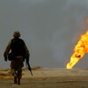 Un soldat américain marche en solitaire vers un puits de pétrole qui brûle.