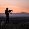 Un homme pointe son arme d'assaut à l'horizon.