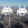 Trois extraterrestres pixelisés au-dessus d'une grande ville.