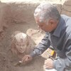 Un archéologue dépoussière une statue.