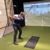 Un jeune golfeur s'élance pour frapper une balle dans un simulateur.