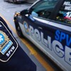 Un policier arbore son écusson d'épaule devant une voiture aux couleurs du SPVM.