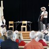 Un jeune homme coiffé d'un chapeau de cow boy chante sur scène.        