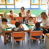 Deux institutrices qui mangent avec des enfants à deux tables différentes.