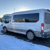 Une fourgonnette est stationnée près d'un autobus.
