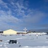 Un village en hiver surplombé d'une grande croix avec un coeur en son centre. 