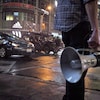 Un assistant tient un porte-voix près de la rue Yonge où est tournée une scène du film Suicide Squad avec une voiture.