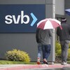 Des passants sous des parapluies marchent devant une succursale de la banque américaine Silicon Valley Bank.