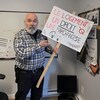 Sylvain Dubé tient une pancarte où il est écrit : Le logement, un droit, pas une marchandise.