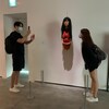 Un homme photographie une femme devant une sculpture.