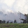 Des soldats se tiennent proches de canons à l'extérieur, alors qu'il y a de la fumée.