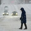 Un homme traverse la rue sous des précipitations de neige.