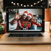 Un couple sur un écran d'ordinateur fête Noël par vidéoconférence avec un cadeau dans les mains. 