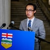 Thomas Dang devant un micro à l'Assemblée législative de l'Alberta.
