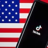 Un téléphone affiche le logo de TikTok devant le drapeau des États-Unis. 