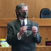 Un homme tient un billet avec le nom de la gagnante.