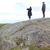 Deux personnes sur un rocher prennent une photo du paysage.